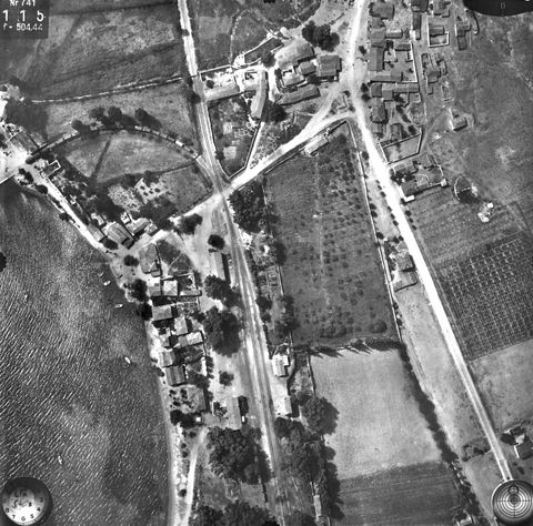 Vertical aerial photo of Myloi station, the village, the road crossing and the curved siding to the pier with a long goods train.