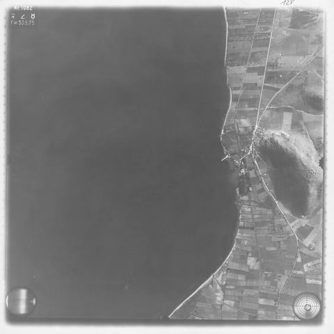 Strip-flight aerial photo (Aufnahme 042): Myloi village at the foot of Mt Pontinos, the long pier, the coastal railway, the station grounds and a shed with two parallel roofs among eucalyptus trees.