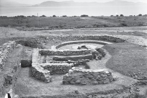 Lerna excavation: the successive apsidal houses D and M seen from the west, with a Second World War machine-gun post in the background, the Myloi–Argos railway, a telegraph pole, the coastal plain and the Argolic Gulf.