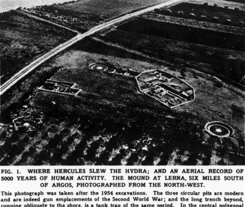 Oblique aerial photo of the mound of Lerna from the northwest after the 1954 season, showing three Second World War gun emplacements, a WWII tank trap running to the shore, the House of Tiles and an orchard.