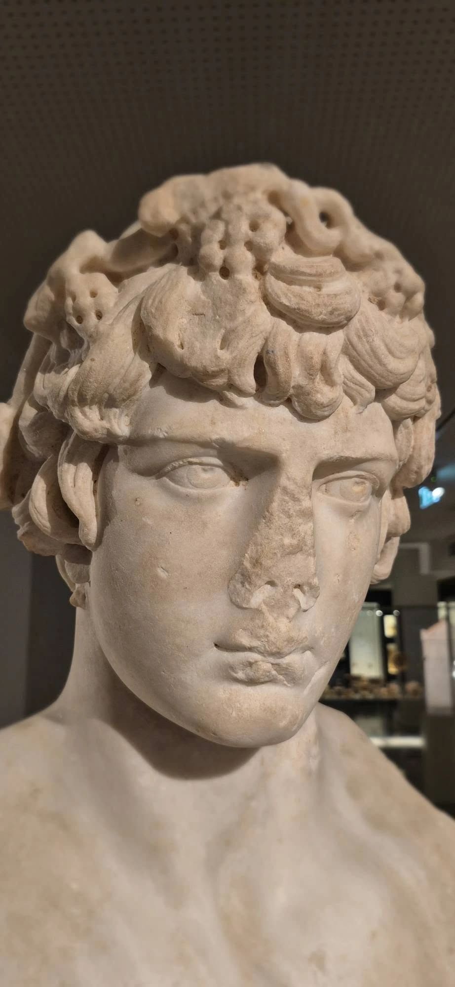 Het marmeren gezicht van Antinoos van dichtbij, met zijn krullen en beschadigde neus, in het Archeologisch Museum van Argos