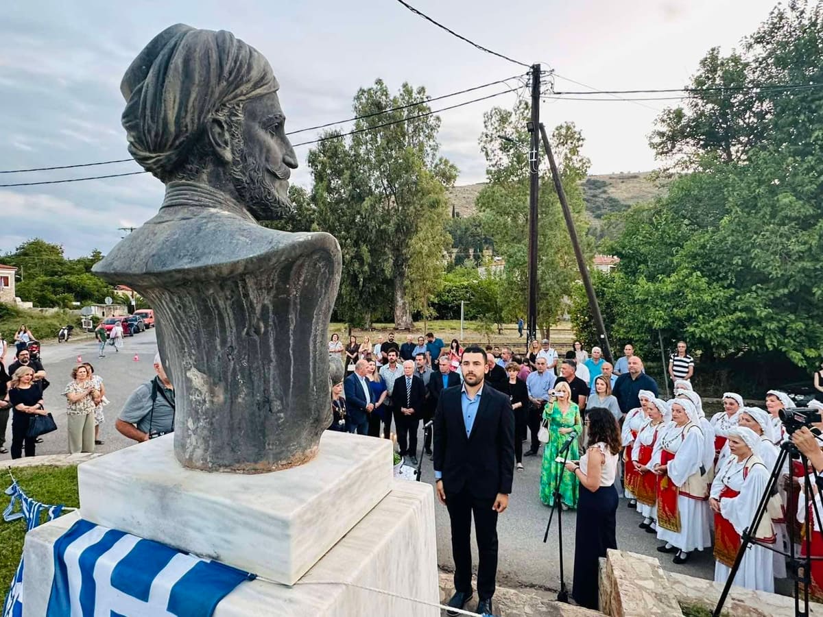 Het bronzen borstbeeld van generaal Makriyannis met een Griekse vlag, en daarachter de mensen die samenkwamen voor de herdenking van 200 jaar, 15 juni 2025