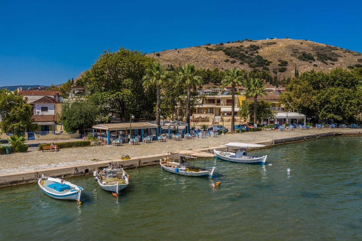 Βάρκες στο λιμανάκι με την παραλιακή και τον Ποντίνο πίσω