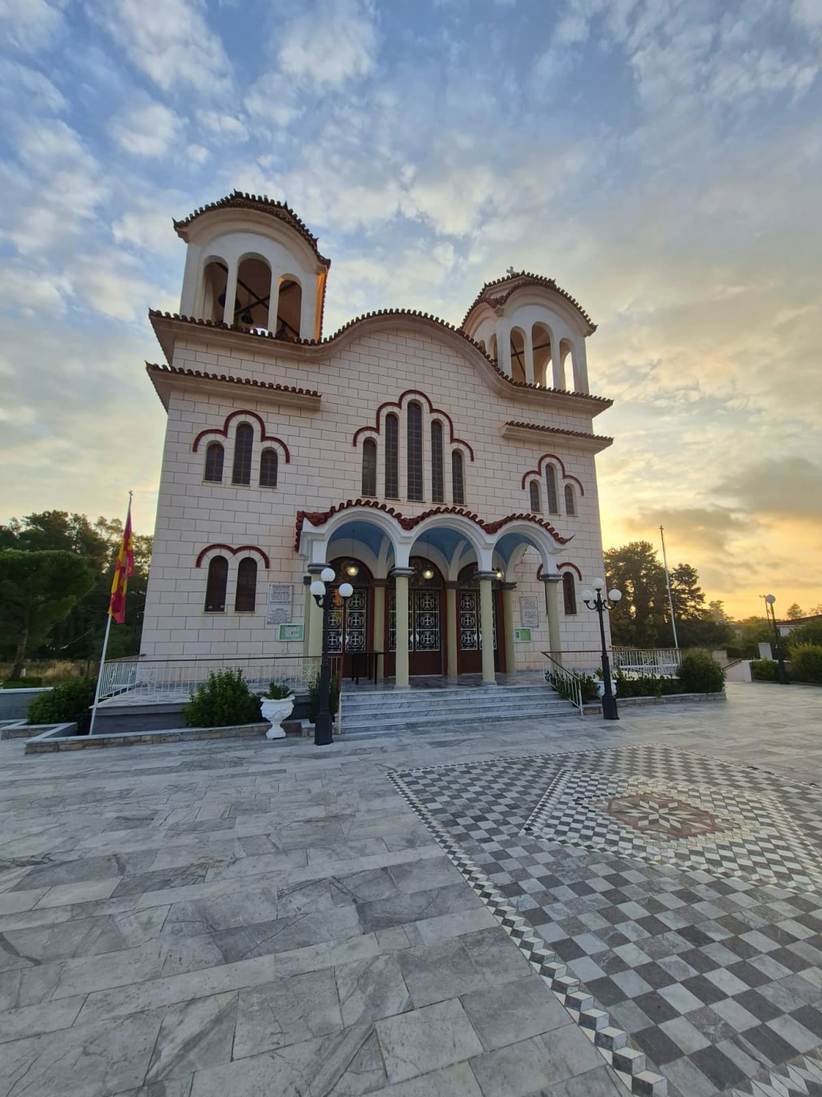 The church of the Holy Apostles in Myloi at sunset, with its two bell towers, arched porch and the marble square in front