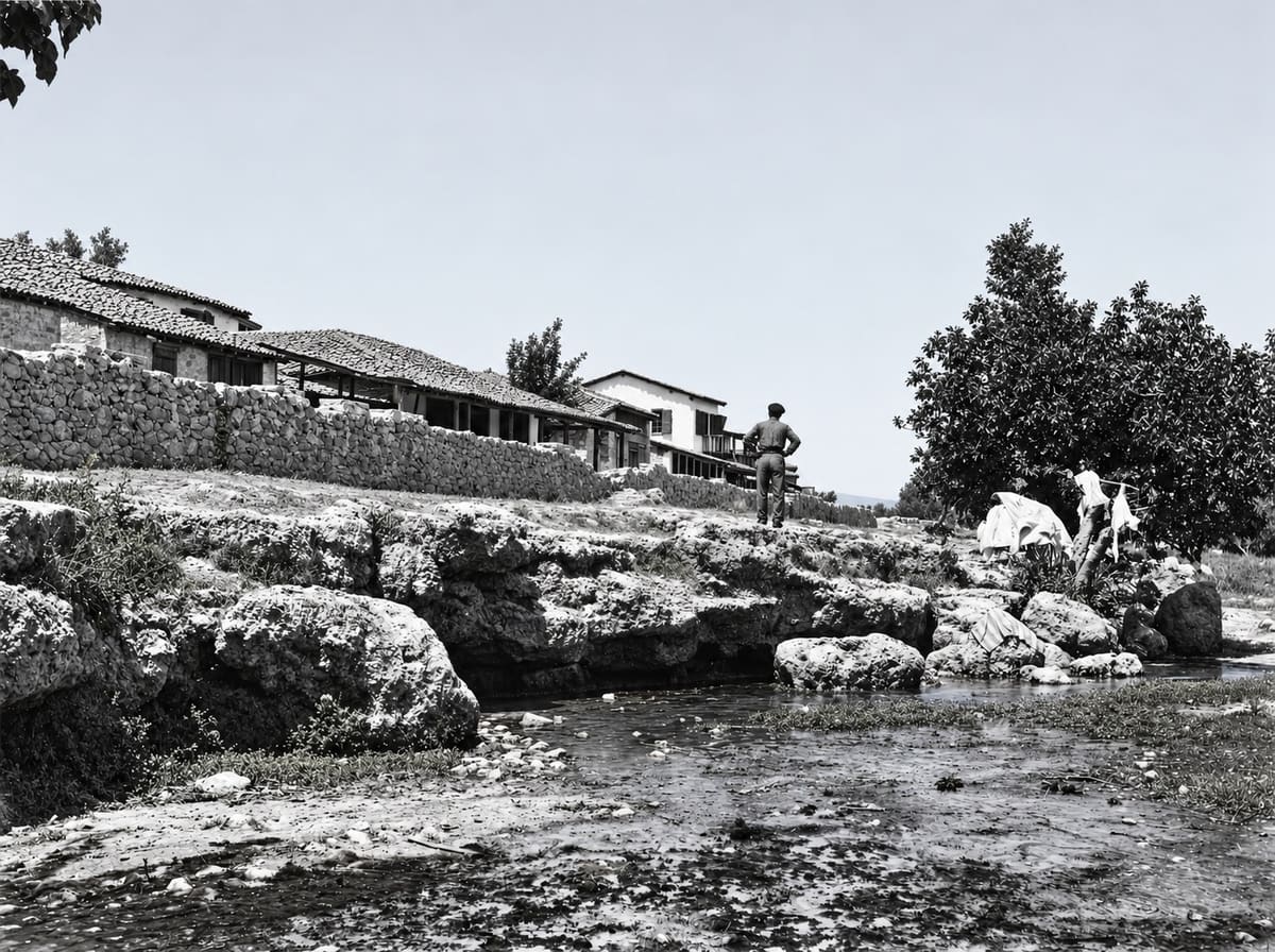 The small southern spring by the church of Agios Dimitrios in Myloi, with a row of houses with wooden verandas, photographed by the Australian archaeologist William Woodhouse sometime between 1890 and 1935. This is roughly how the village looked that Mila and Stavros left behind.