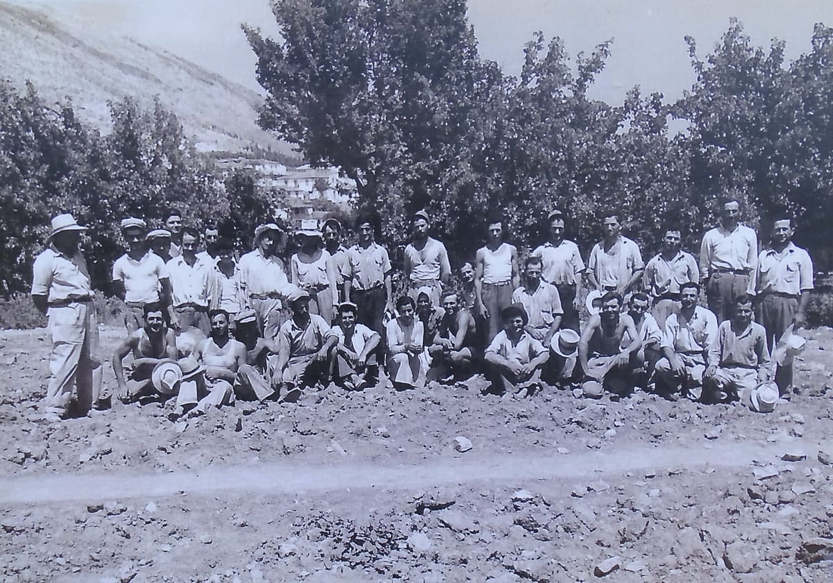 The staff of the 1954 American excavation at Lerna, some forty people standing and kneeling on bare ground below the trees