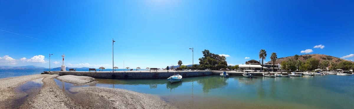 Panorama of the pier and beach of Myloi under a clear blue sky