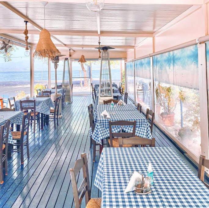 Covered terrace of the Five F fish taverna with checked tablecloths and a view of the sea
