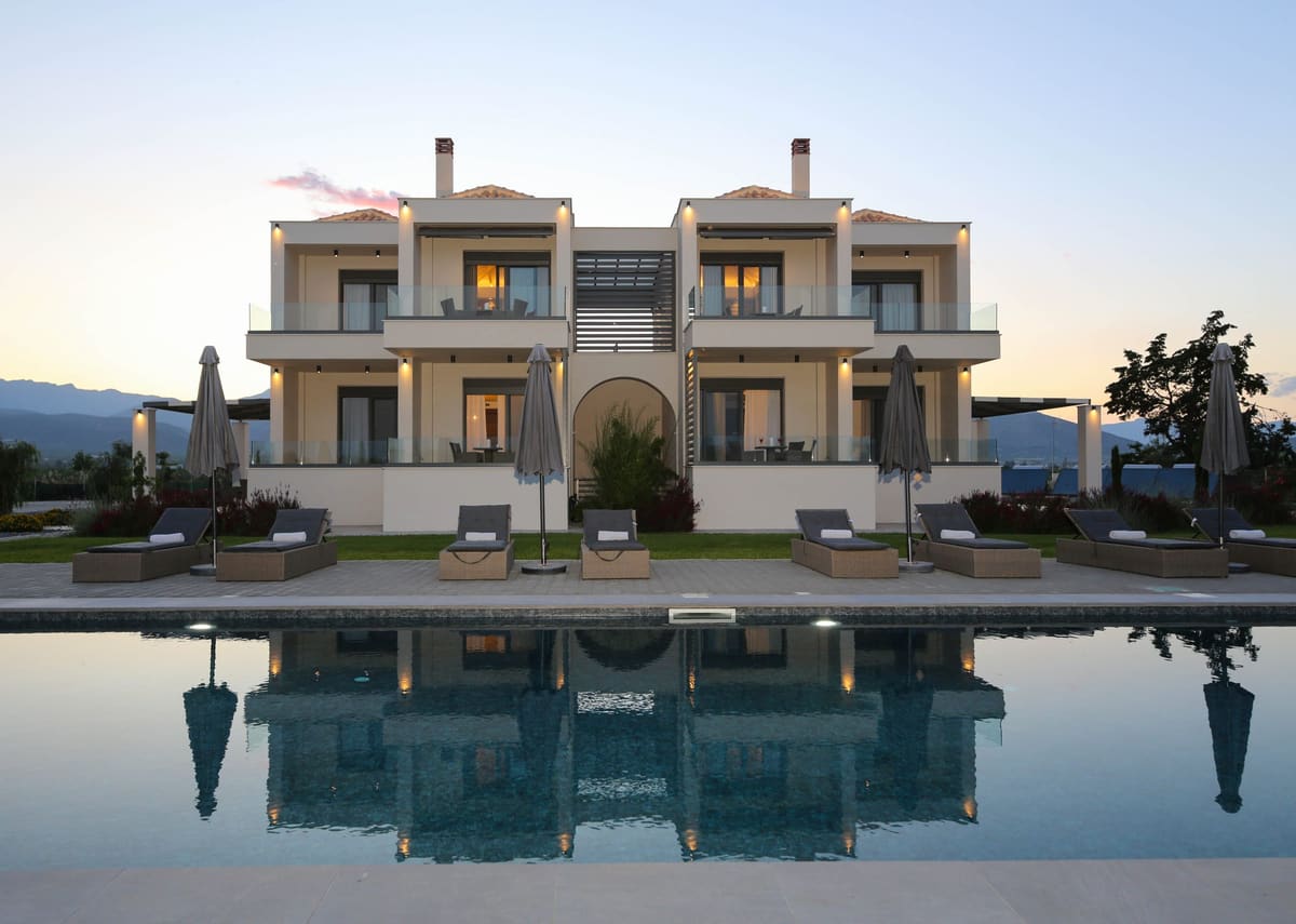 The two-storey residences with tiled roofs and balconies, reflected in the swimming pool in soft evening light