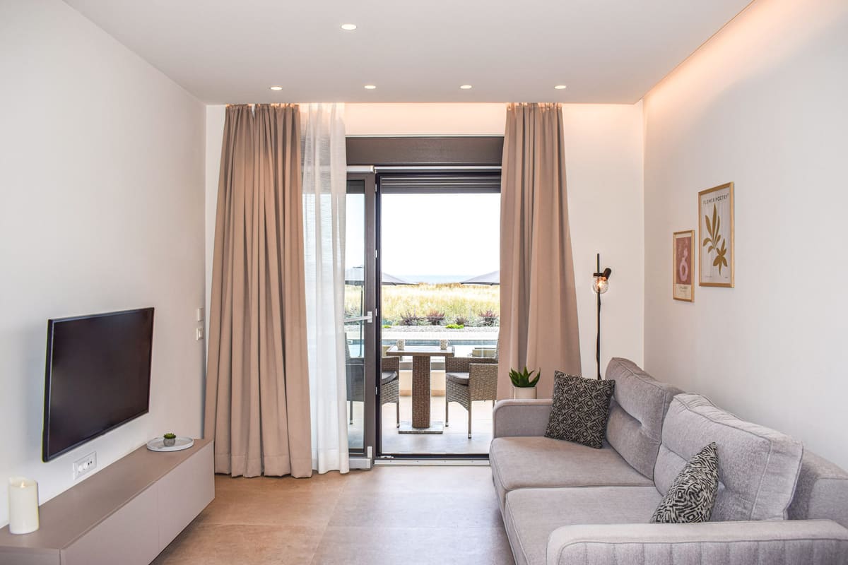 Light, minimalist living room with a sofa, a TV and the balcony door open to the view