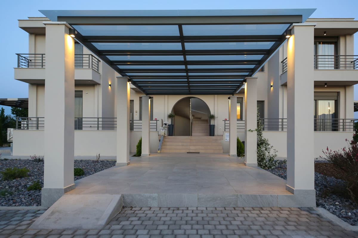 The paved walkway under a modern pergola between the two residence buildings