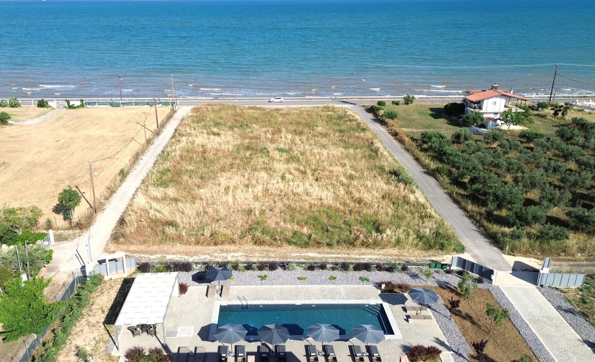 Aerial view of the estate with its pool and gardens, the coast road and the beach and sea right behind
