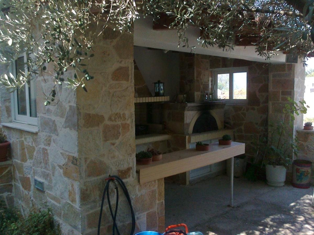 Πέτρινη ψησταριά και εξωτερική κουζίνα κάτω από μια ελιά στην αυλή