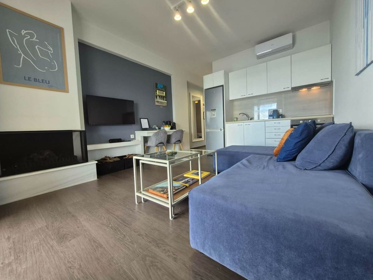 Living area with a blue corner sofa and the open kitchen