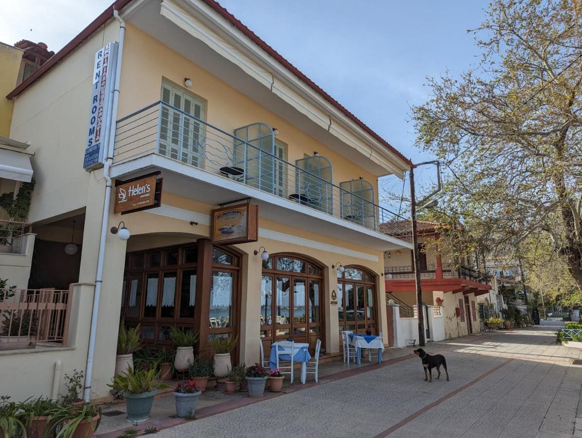 Το κρεμ κτίριο του Helen's Rooms στον παραλιακό δρόμο, με μπαλκόνια πάνω από τα τοξωτά παράθυρα της ταβέρνας