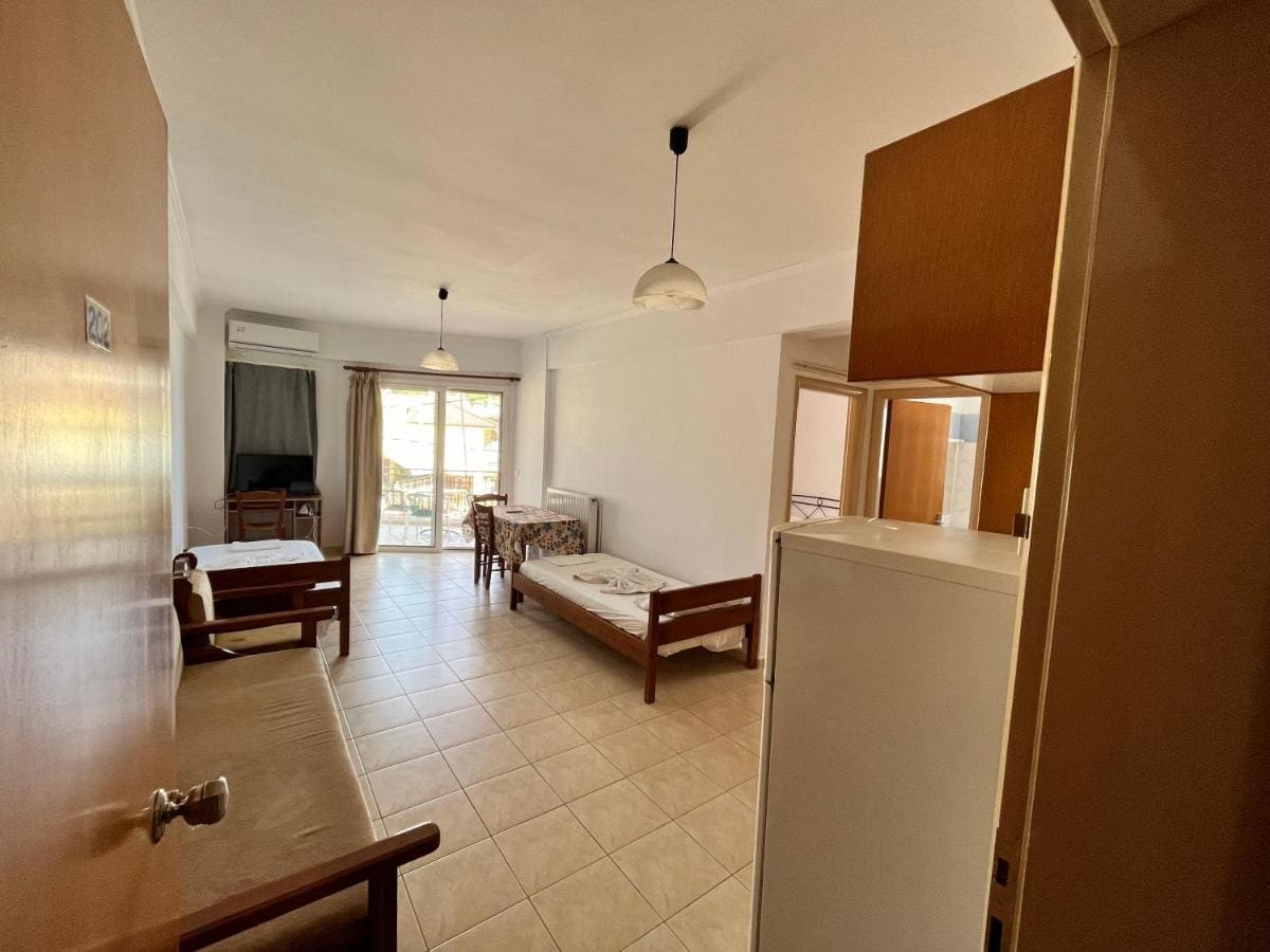 Studio with a kitchenette, a small dining table, beds by the window and a door to the balcony