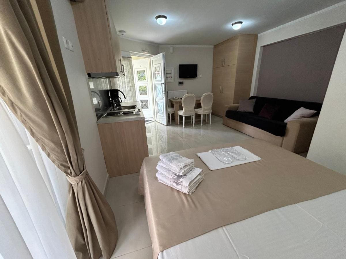 Appartement met een tweepersoonsbed en opgevouwen handdoeken, een keukenhoek, een eettafel en een deur naar het balkon