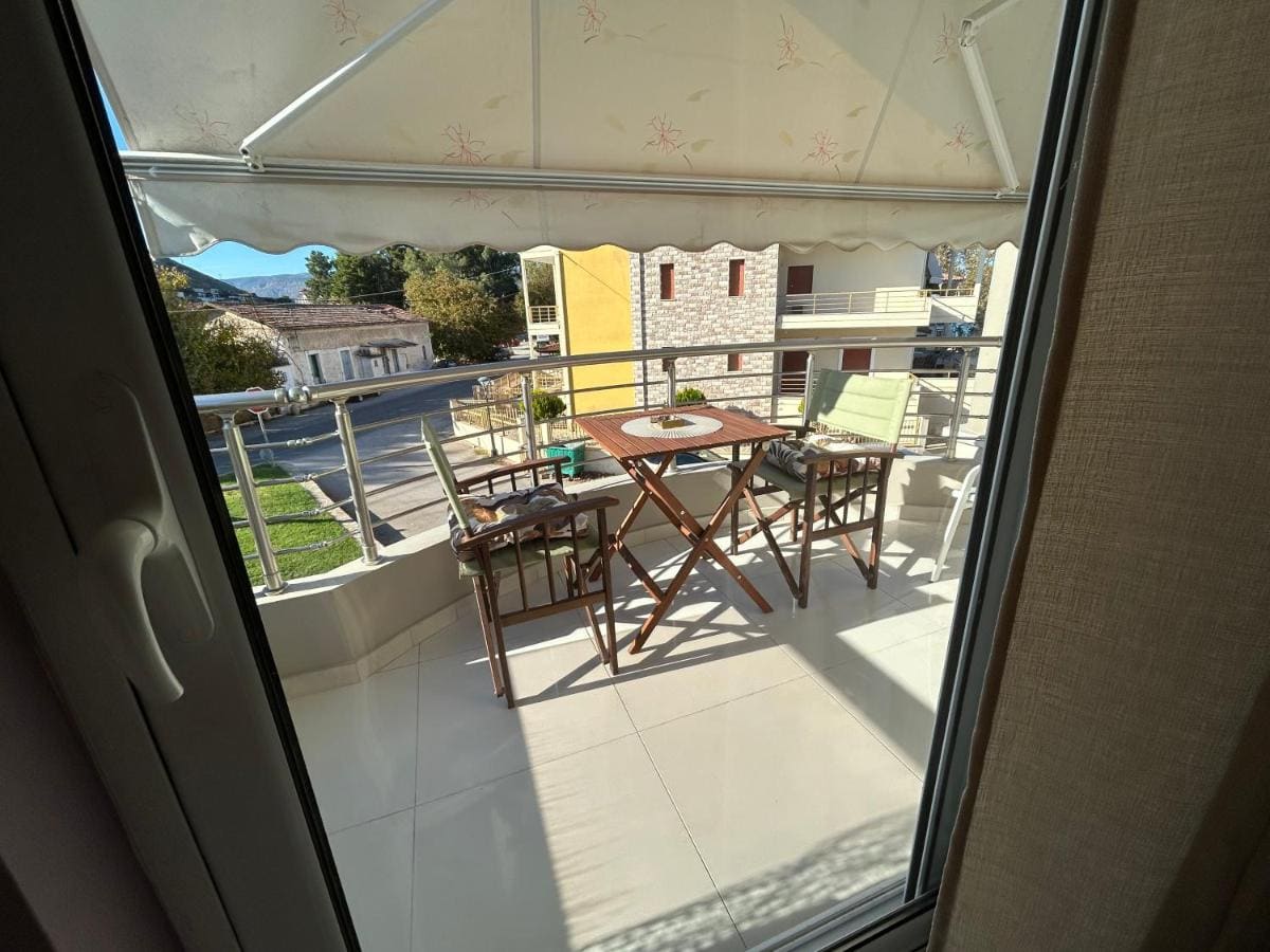 Overdekt balkon met een houten tafel en stoelen onder een zonnescherm, gezien door de open balkondeur