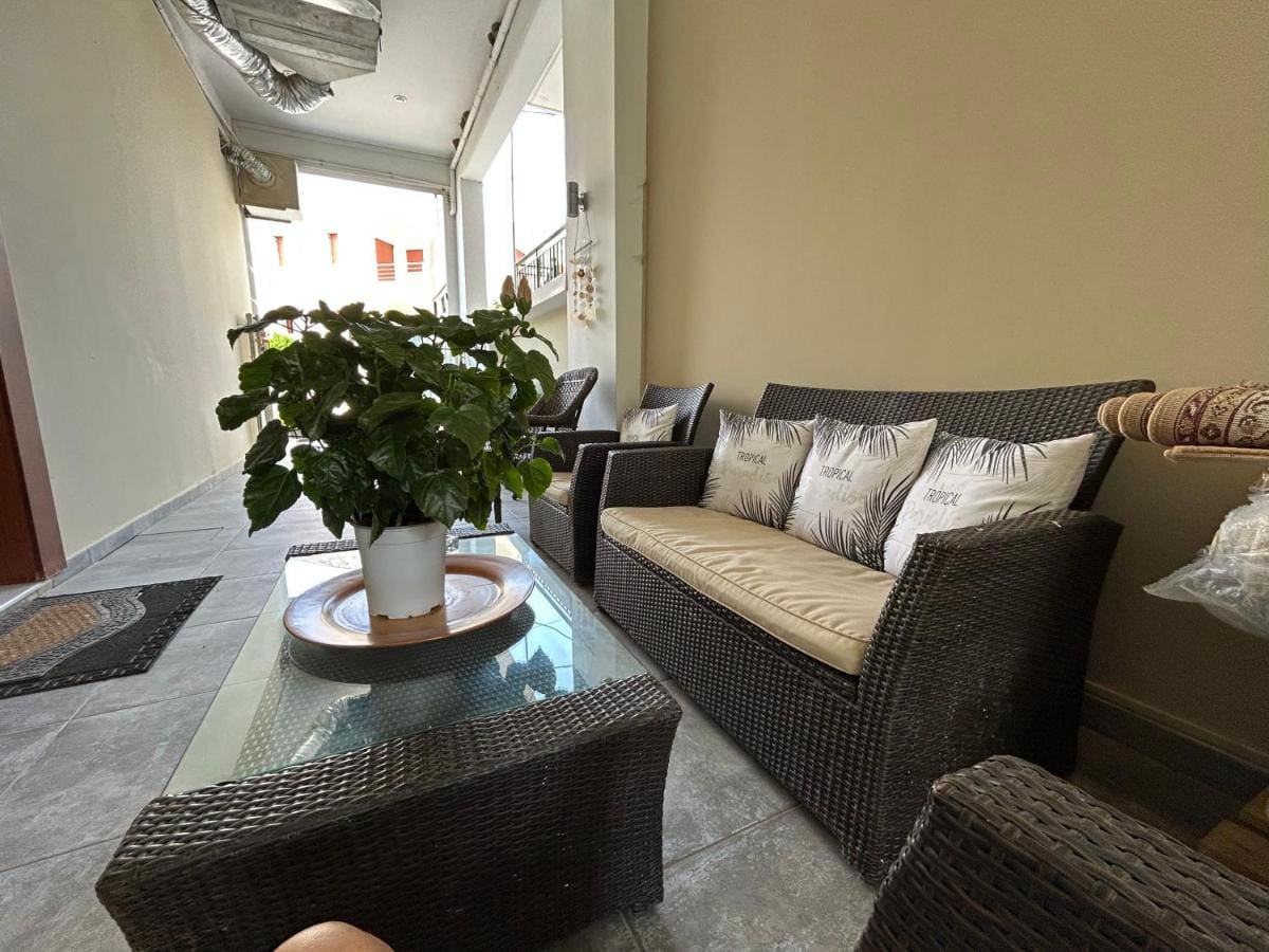 Buitenlounge met rieten banken en kussens rond een glazen tafel met een plant