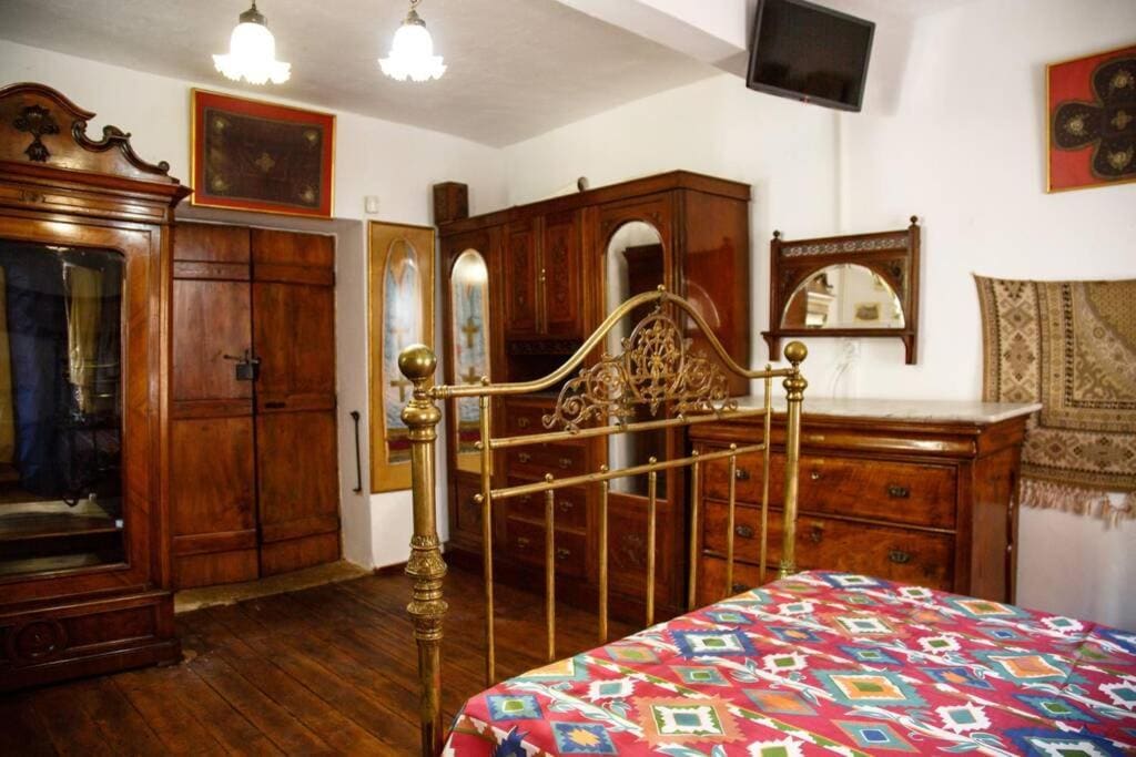 Bedroom with an old brass bed, a large wooden wardrobe and a colourful patterned bedspread