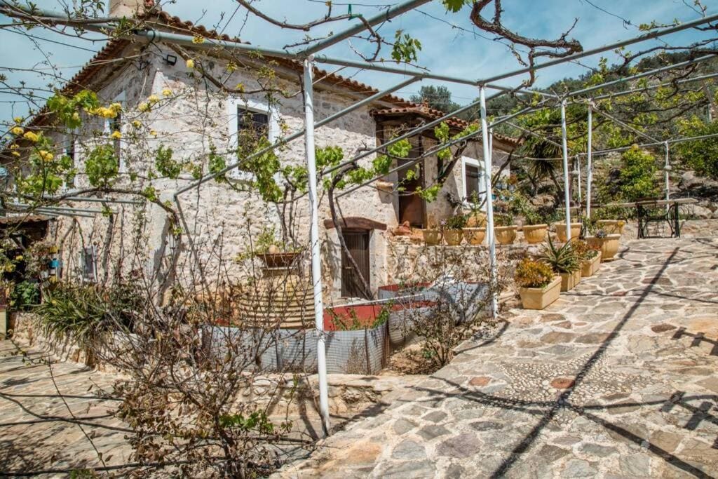 Stone-paved courtyard under a pergola in front of the old stone house