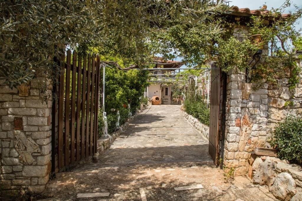 An old wooden gate in a stone wall, opening onto a shady path to the house