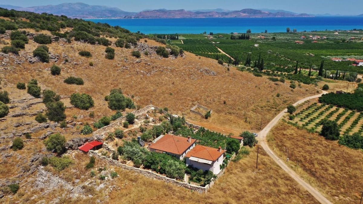 The villa with its red roofs from the air, in the dry hills above Myloi, with orchards, the plain and the blue Argolic Gulf beyond