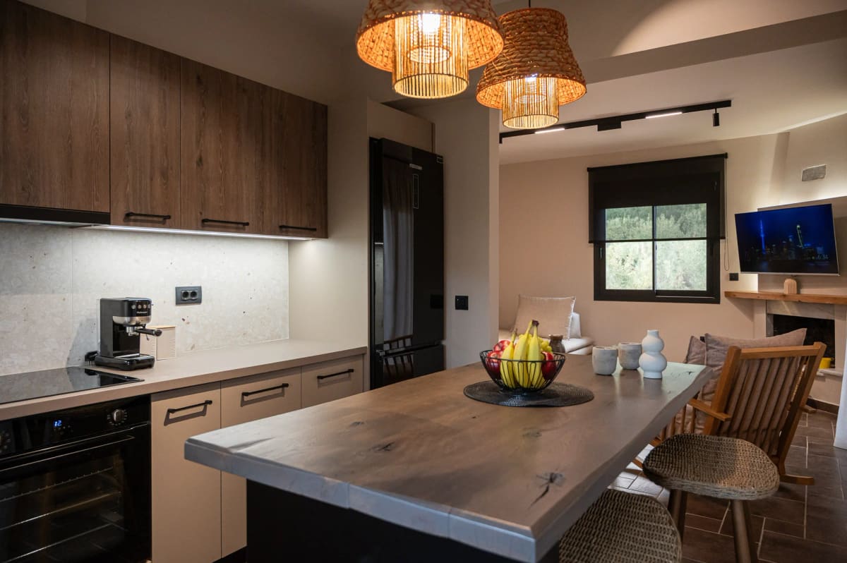 Kitchen with dark wooden cabinets, a wooden island with a fruit bowl and woven pendant lamps