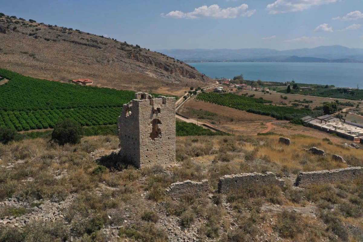 Ο Πύργος της Βασιλοπούλας με τα ερείπια του περιβόλου, πορτοκαλεώνες από κάτω και τον Αργολικό κόλπο στο βάθος